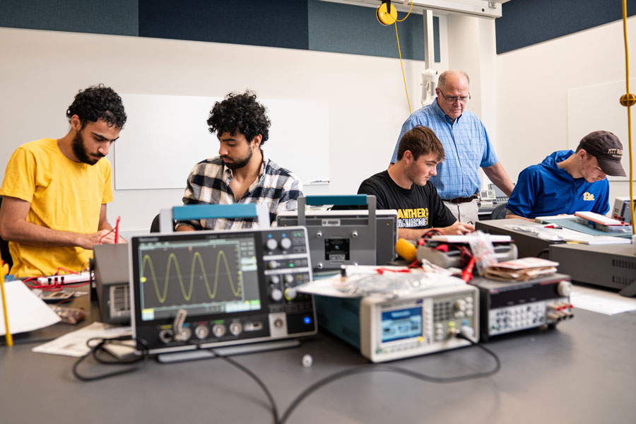 Students with professor using electronics testing equipment