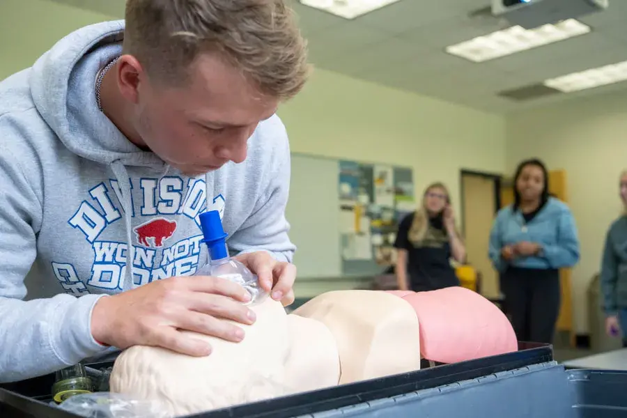 Student practicing breathing exercises on a mannequin