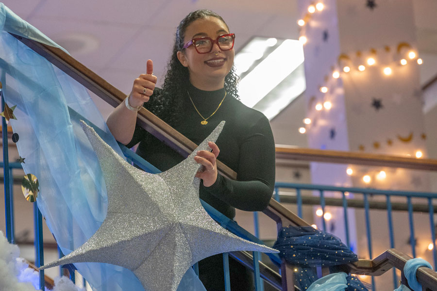 Girl holding a large star and giving a thimbs up.