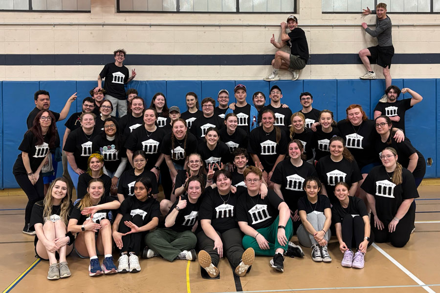 Fraternity and sororitie members sitting in the gym.