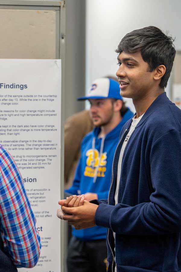 Pre-medicine student standing in front of his poster about doom scrolling