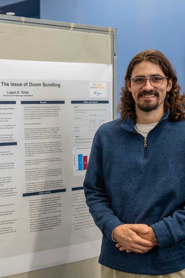 Student standing in front of his research poster on Doom Scrolling