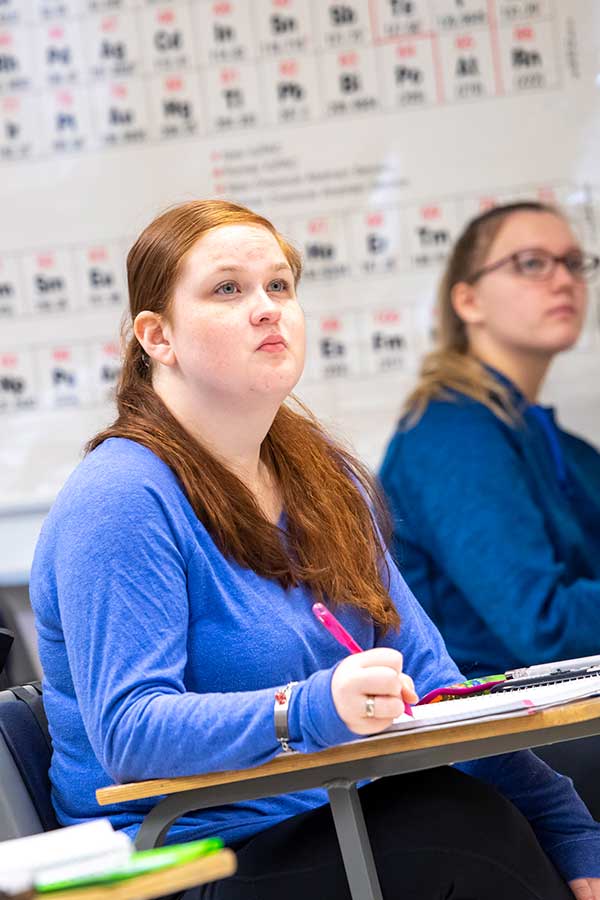 Student in front of periodical chart