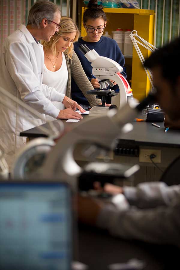 Professor with students at microscope