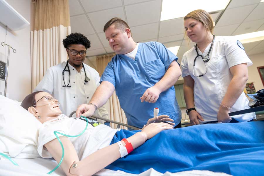 Nursing students with a professor practicing exercises on a dummy