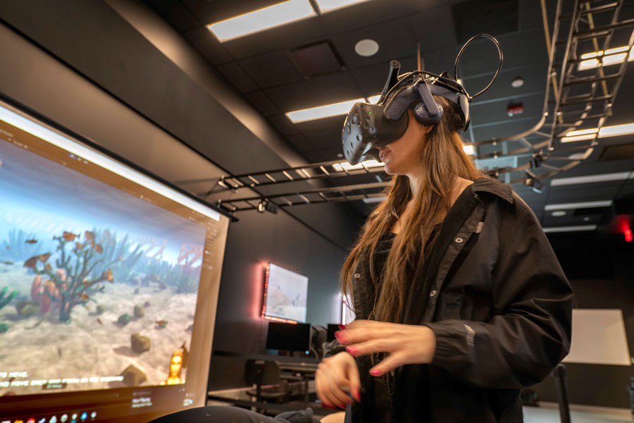 A student using a VR headset in front of a projector screen