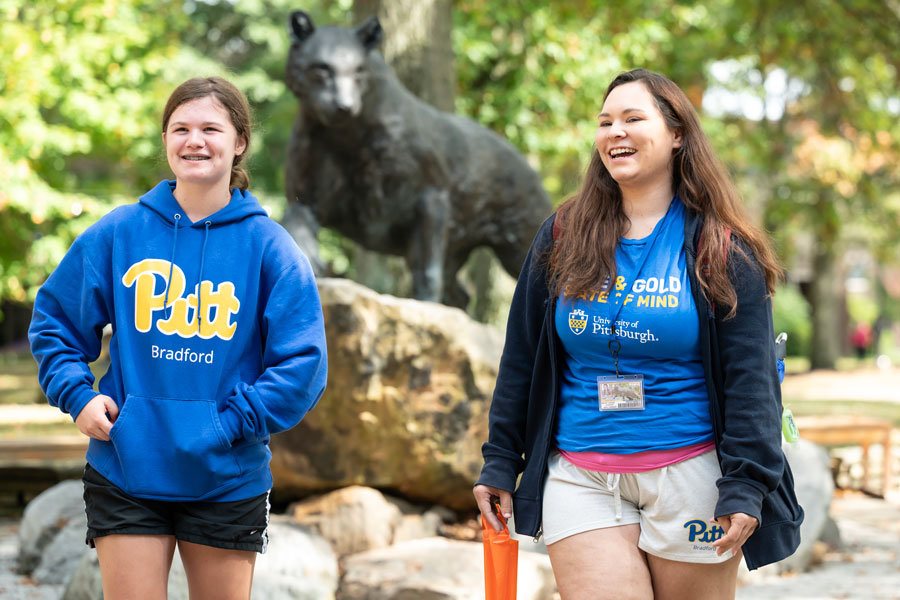 Two students walking in front of the panther statue in the quad