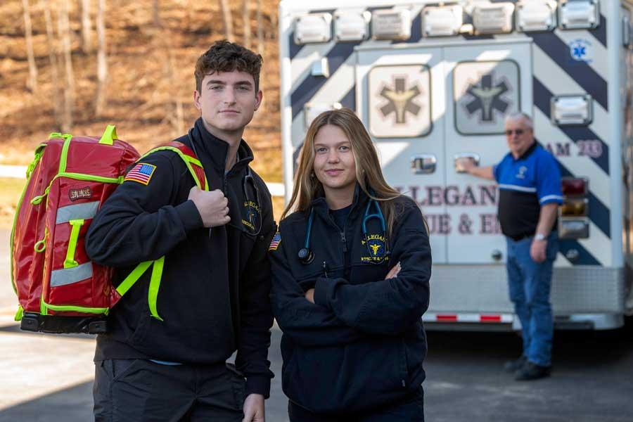 Two students standing behind an ambulance