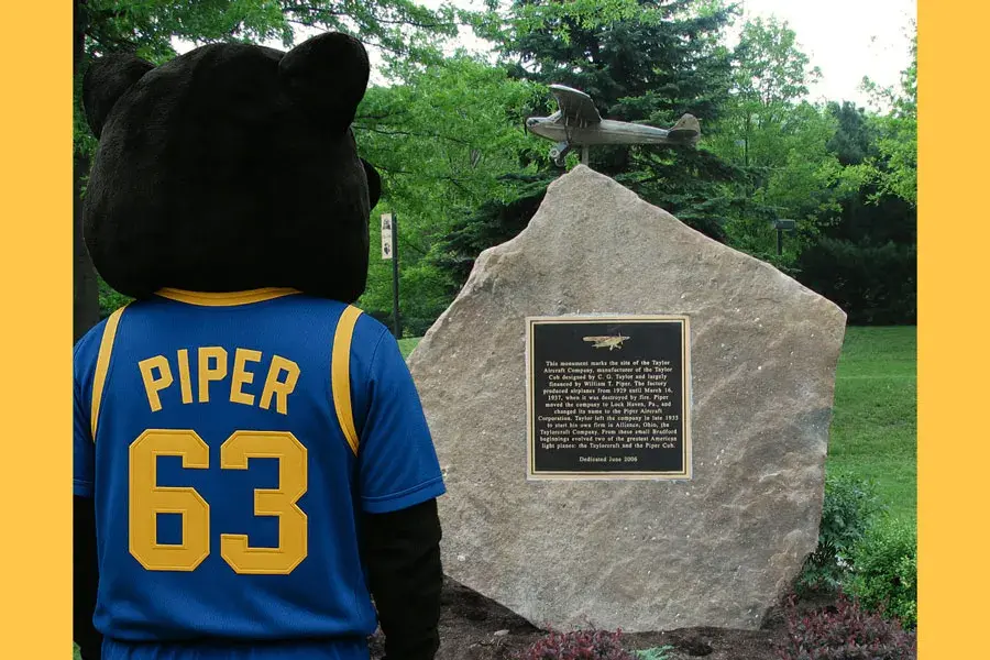 The panther mascot, Piper, looking at the Taylor Aircraft memorial statue