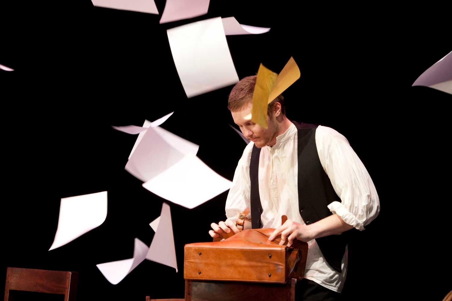 Student standing at podium with papers flying through the air