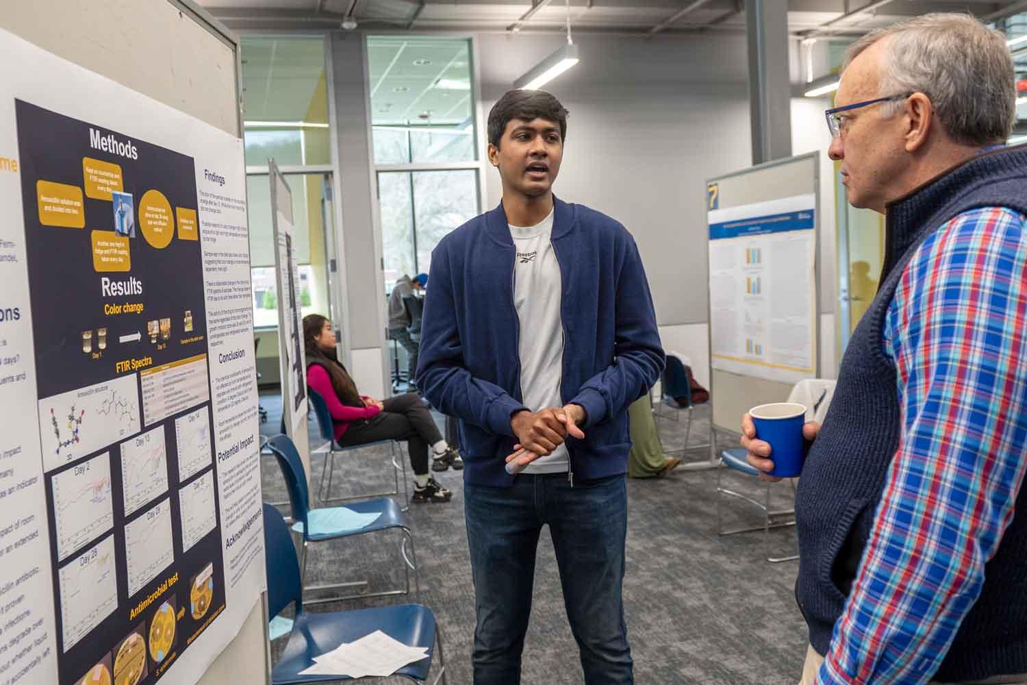 Madhav Ellini discusses his research on the stability of amoxicillin with Pitt-Bradford President Rick Esch.