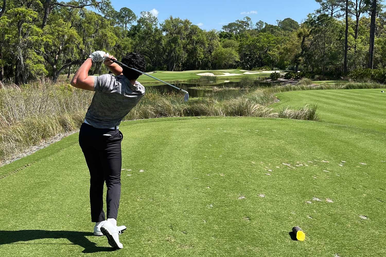 Drew Heinze on a golf course swinging at a ball