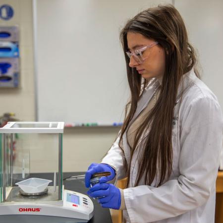 Gabriella working in the lab with a beaker and other equipment