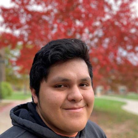 A photo of Ty Bowen in front of a colorful, red tree