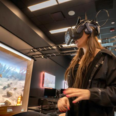 A student using a VR headset in front of a projector screen