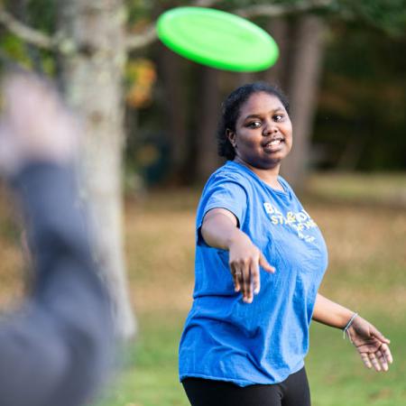 a student throwing a frisbee to a friend