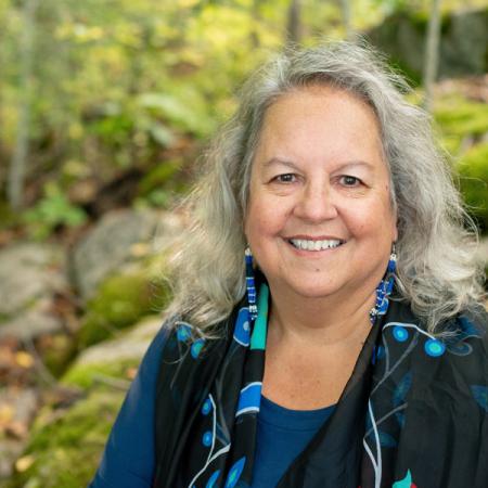 Robin Kimmerer in front of a nature scene, smiling