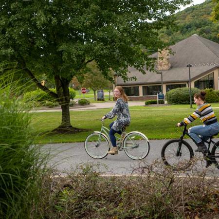 Two students riding their bikes on campus