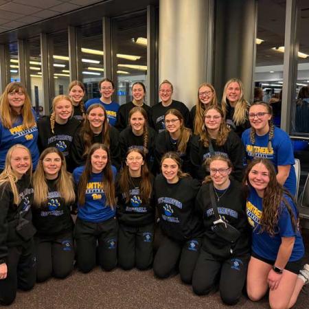 The UPB women's softball team smiling for a group photo in the airport