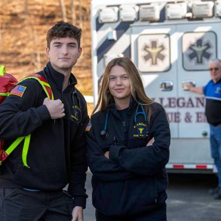 Two students standing behind an ambulance