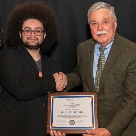 Gabirel Jakovlic standing with James K. Evans with his award