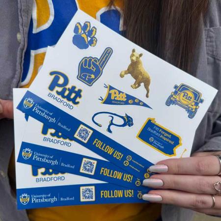 A person holding the sticker sheet that includes stickers from the university
