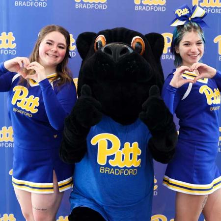 2 Cheerleaders standing with the panther mascot